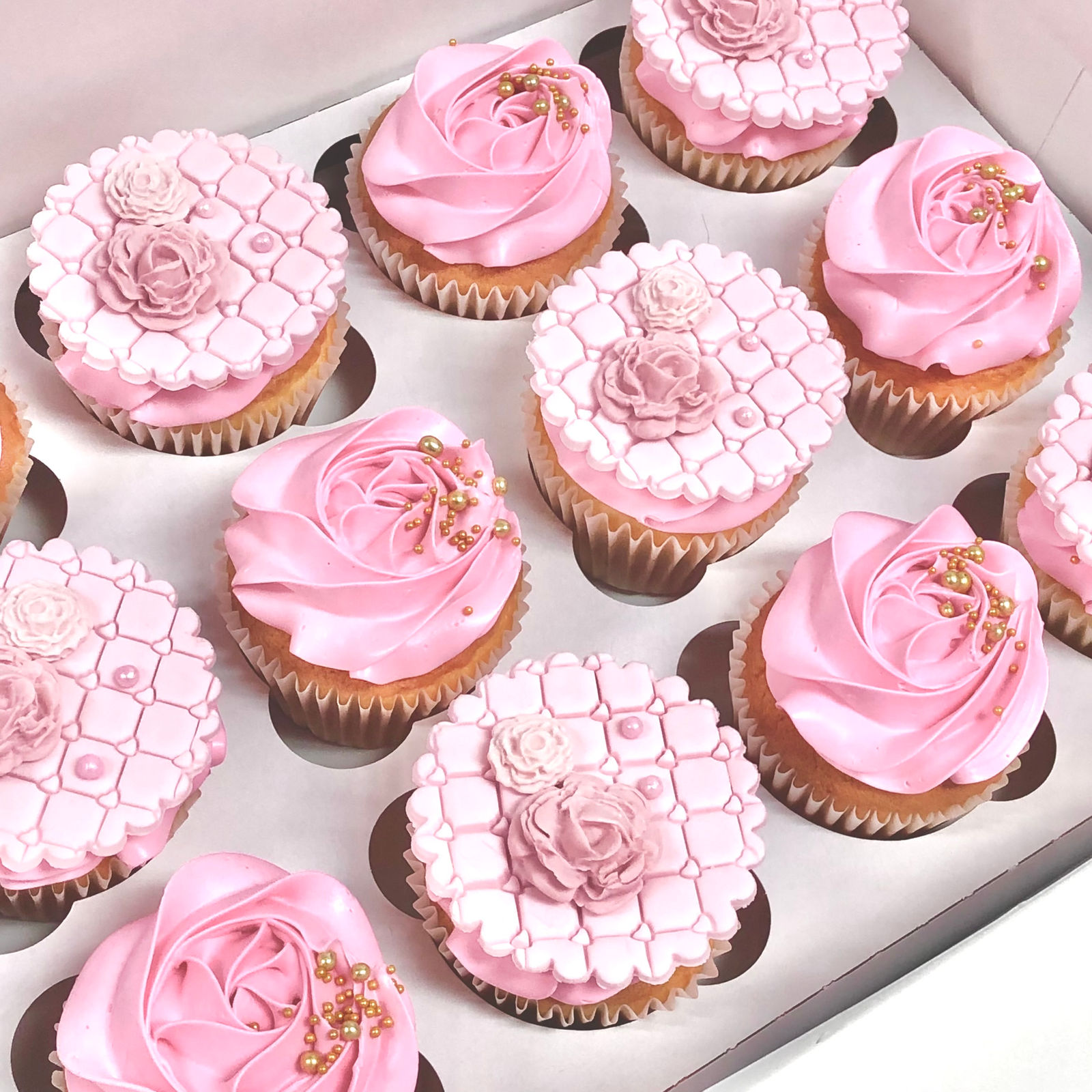 A box of cupcakes piped with pink buttercream swirls